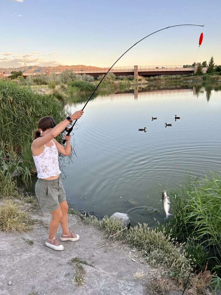 teen girl catching catfish riverfront pond 6 29 24